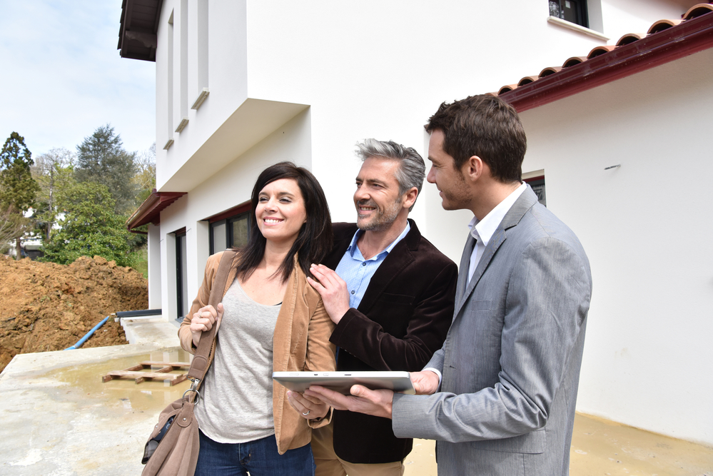 Couple with realtor visiting house under construction